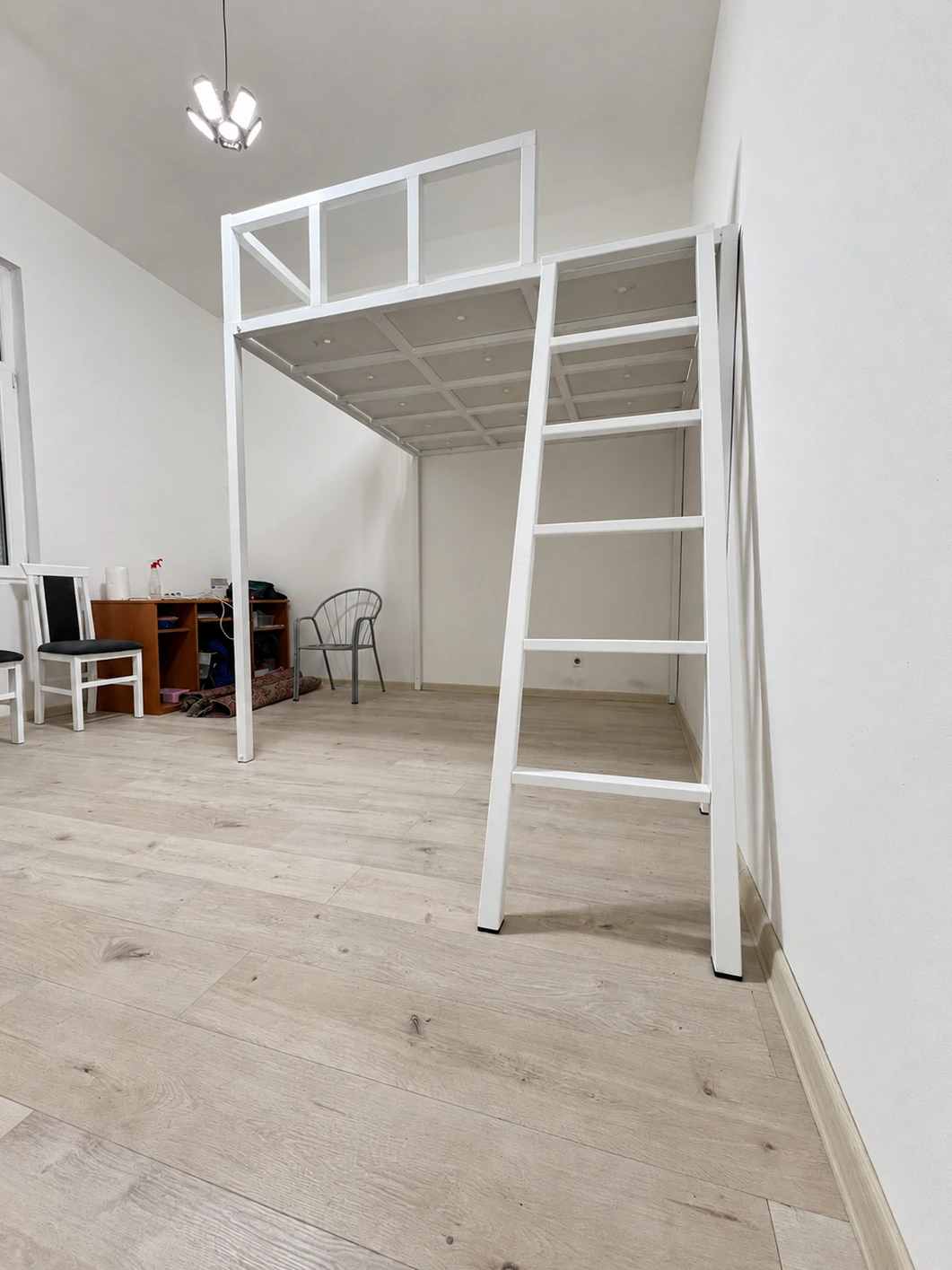 White metal double bed without a mattress — view from the ladder side